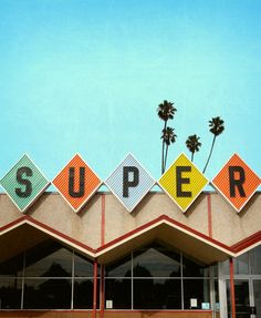 a building with the word super painted on it's side and palm trees in the background