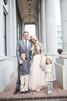 a family poses for a photo in front of an old building with columns and pillars