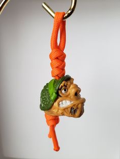 a keychain with a dog head and green leaves on it, hanging from a hook