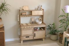 a child's wooden play kitchen with potted plants