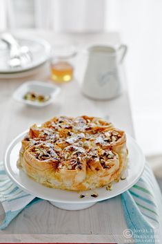 a white plate topped with a pastry covered in toppings on top of a table