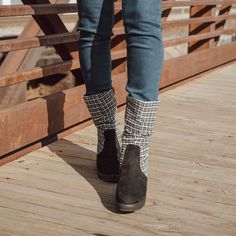 a person wearing boots and jeans walking across a bridge