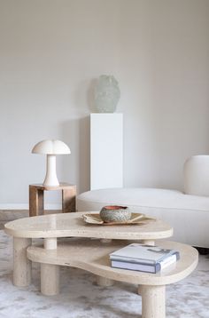 a living room with a white couch, table and lamp on the floor in front of it