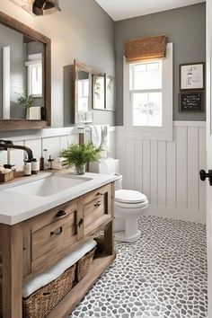 a white toilet sitting next to a sink in a bathroom under a mirror above a wooden vanity