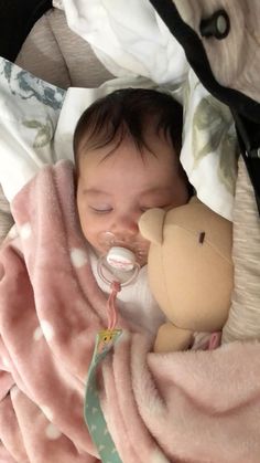 a baby is laying down with a stuffed animal in it's mouth and wearing a pacifier