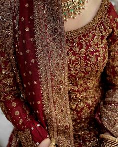 a woman in a red and gold dress with jewelry on her neck, wearing a tiara