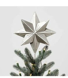 a silver star decoration on top of a small christmas tree with lights in the bottom