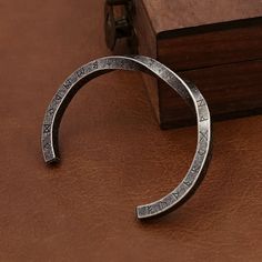 a silver cuff with roman numerals on it sitting next to a wooden box