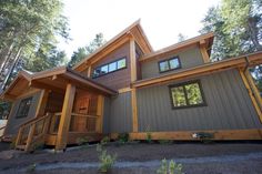 a house in the woods with lots of windows and wood trimmings on it