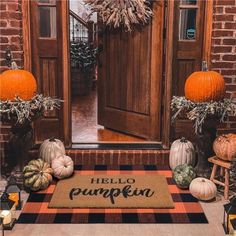 pumpkins and gourds are sitting on the front door mat that says hello pumpkin