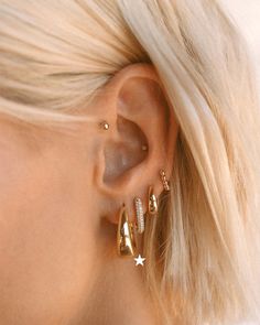 a close up of a person wearing gold earring with diamonds on the side and in front of her ear