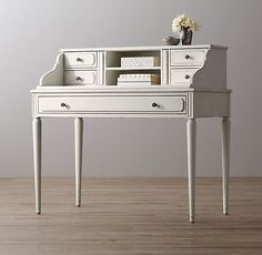 an old white desk with drawers and a cup on top is shown in front of a gray wall