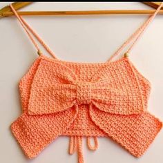 an orange crocheted top with a bow on it