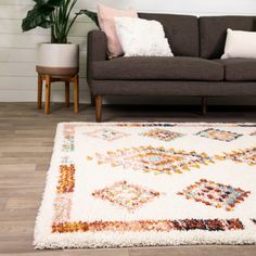 a living room with a brown couch and white rug on the floor, potted plant next to it