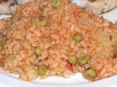 rice and peas on a white plate with other food items in the backgroud