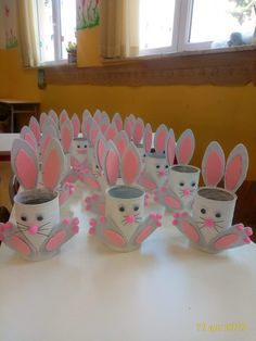 a table topped with lots of cups filled with pink and white bunny ears on top of each other