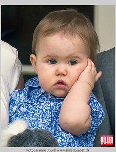 a baby is sitting in a car seat with his hand on his head and looking at the camera