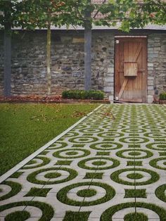 an outdoor area with grass and stone walls, surrounded by green lawning circles in front of a wooden door