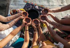 a group of people sitting around each other with their hands on top of the bowls