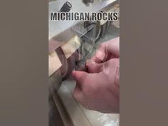 a person is cutting something with a pair of scissors in front of the words michigan rocks