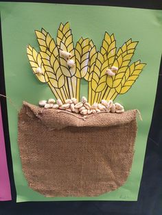 a paper bag with some yellow flowers in it on a green and pink background that is made to look like corn stalks