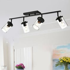 three lights are hanging from the ceiling above a dining room table with chairs and a vase