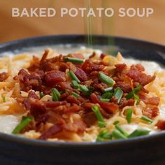 baked potato soup with bacon and chives in a black bowl on a wooden table