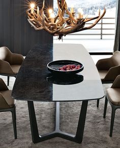 a dining room table with chairs and a bowl of fruit on the plate in front of it