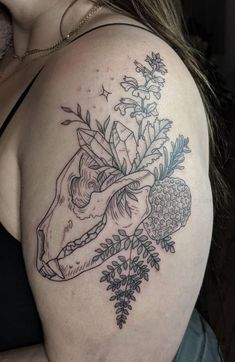 a woman's shoulder with flowers and a cow skull tattoo on her left arm