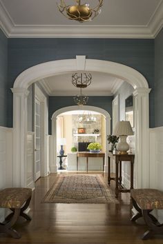 an archway leading into a living room with two benches and a rug on the floor