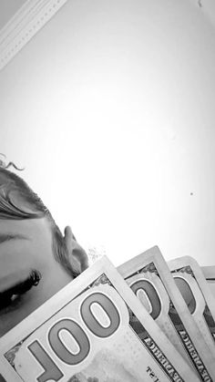 black and white photograph of woman hiding behind stacks of $ 100 bills in front of her face