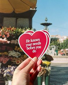 someone holding up a heart shaped sticker that says he knows your needs before you do