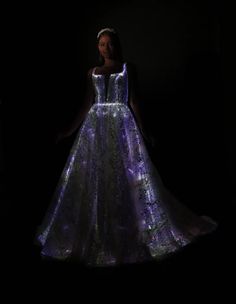 a woman in a dress that is lit up with purple and green lights on it