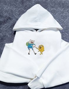 Indulge in nostalgia with our custom-stitched Adventure Time hoodie, embodying the essence of your favorite cartoon duo, Finn & Jake.Looking for a unique gift for a fellow adventurer? Look no further! This personalized cartoon hoodie is sure to bring a smile to the face of any Adventurer. Embrace the Y2K aesthetic with a nostalgic twist and make a statement. Available in sizes S, M, L, and XL, this oversize hoodie ensures a comfortable fit for everyone. Made from a blend of 90% cotton and 10% po Cotton Cartoon Print Hoodie, Cotton Hoodie With Cartoon Print For Streetwear, Cotton Cartoon Print Hoodie Sweatshirt, Cotton Hoodie With Cartoon Print, White Hooded Hoodie With Cartoon Print, White Hoodie With Cartoon Print, White Hooded Hoodie With Embroidered Graphics, White Embroidered Hoodie For Streetwear, White Hooded Sweatshirt With Custom Embroidery