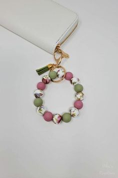 a white purse with a pink and green beaded bracelet hanging from it's side