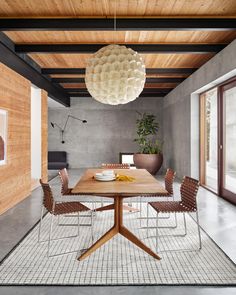 a dining room table with chairs and a light fixture hanging from it's ceiling