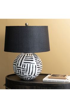 a black and white lamp sitting on top of a wooden table next to a book