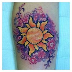 a colorful sun tattoo on the leg with pink and yellow flowers around it's center