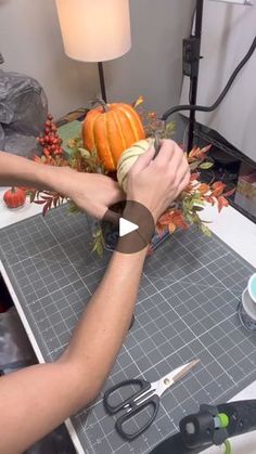 a person is cutting up some pumpkins on a table with scissors and tape around them