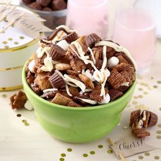 a green bowl filled with chocolate cereal and marshmallows on top of a table