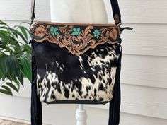 Cowhide Crossbody Purse Handbag Western Bag Turquoise Black Brown Cow Hide Western Tooled Leather This gorgeous bag is crafted in Genuine Cowhide Hair on Skin and features natural cow print. The bag features real leather back with a zip pocket. Tooled leather details adorn the bag on both sides and the strap. Inside is cloth lined with a zip pocket and 2 open pockets. Makes a great everyday bag and great gifts Size: 12 Inches x 10 Inches Light weight design; can be comfortably carried all day Du Western Purses And Handbags Leather, Western Purses And Handbags, Purses Western, Western Bags Purses, Western Bags, Western Purses And Handbags Fabric, Western Cowhide Purse, Cowhide Fringe Crossbody Bag, Western Bag