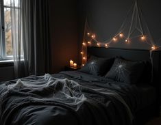 a bed in a dark room with some lights on the headboard and two windows