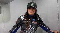 a woman in a black and blue racing suit is posing for a photo with her hands on her hips