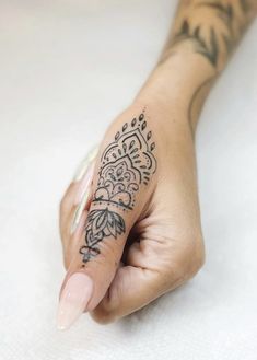 a woman's hand with a tattoo on her left arm and the other half of her finger