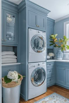 a washer and dryer in a blue laundry room with wood flooring, cabinets and drawers