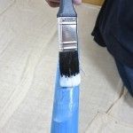 a person is holding a paintbrush with blue bristles and white bristles on it