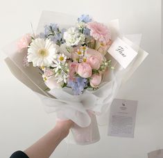 a person holding a bouquet of flowers with a note attached to the back of it