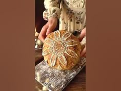 a person holding a loaf of bread on top of a table