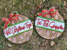 two decorated christmas ornaments sitting in the grass with words written on them and bows around their necks