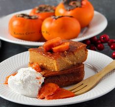 two white plates with food on them next to some tomatoes and other fruit in the background